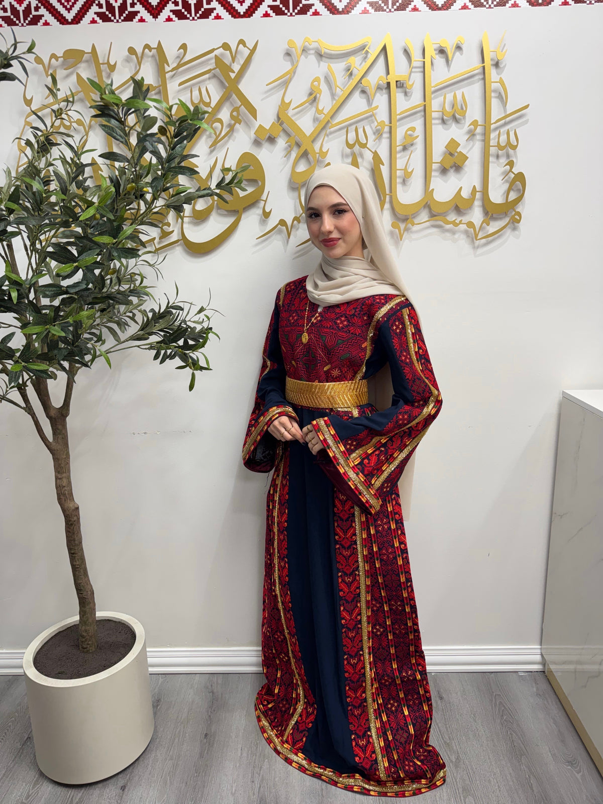 Model wearing a navy Palestinian thobe with vivid red tatreez embroidery